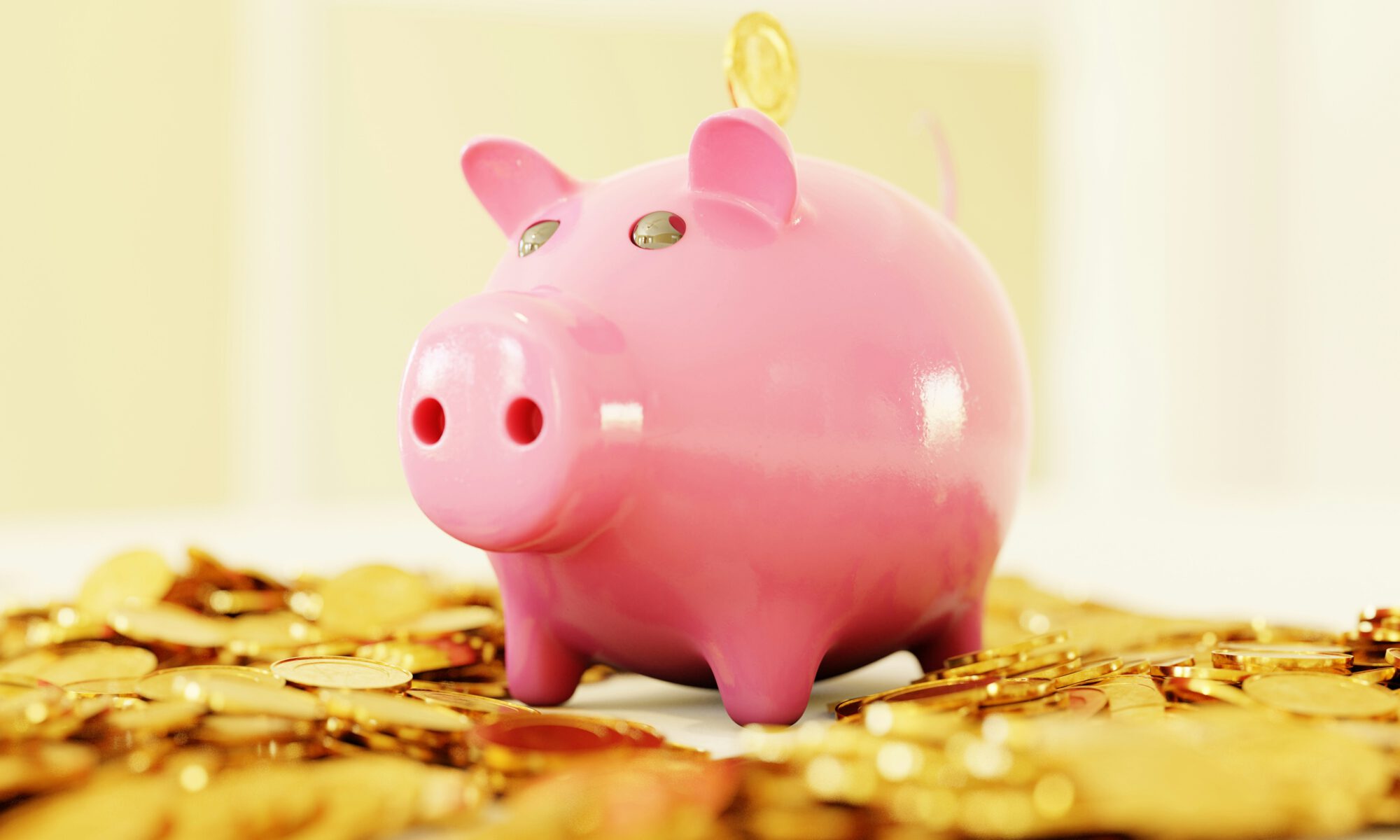 A piggy bank surrounded by gold coins and coins dropping into the bank