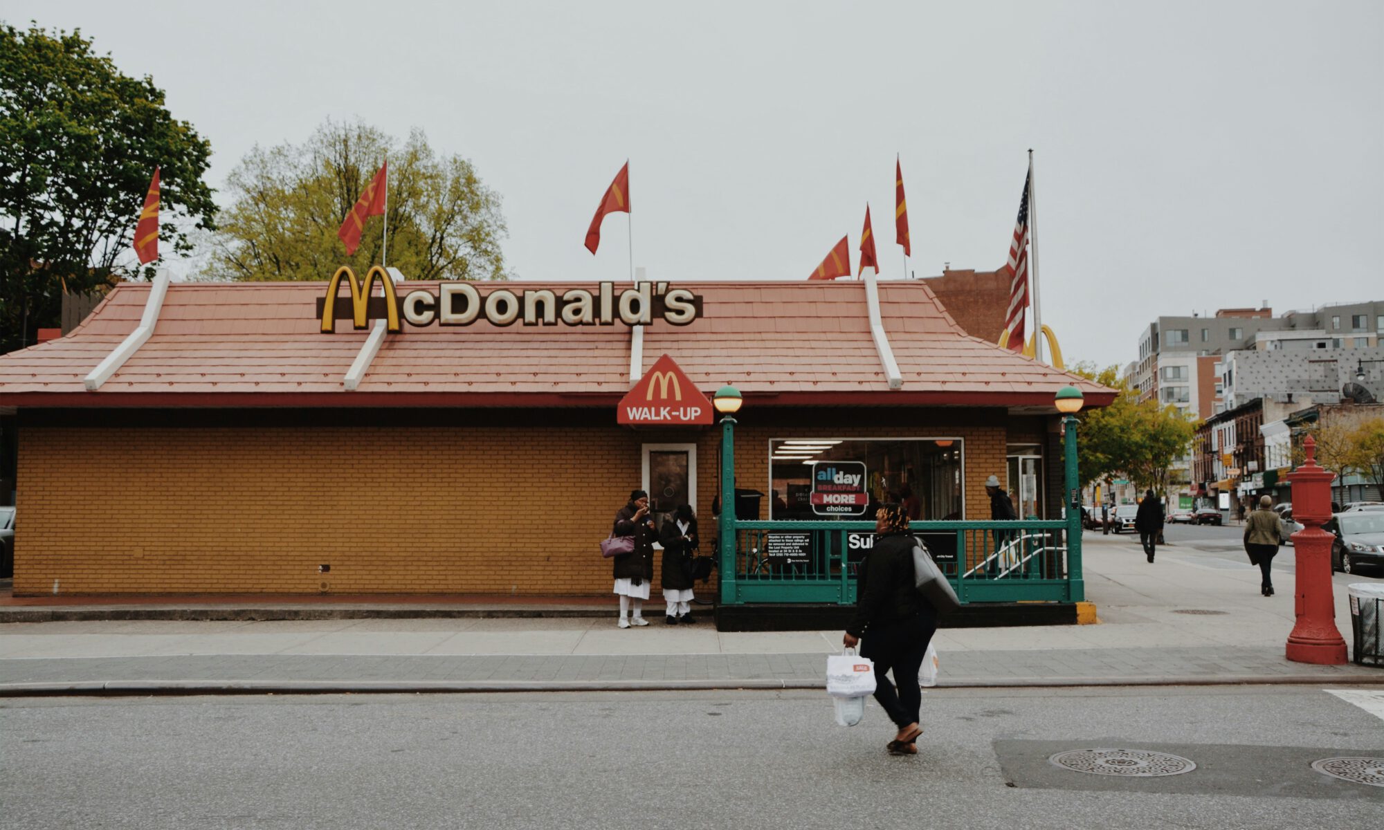 A woman is walking up to an American style Mc Donalds.